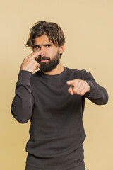 I am watching you. Young confident Indian man pointing at his eyes and camera, show I am watching...