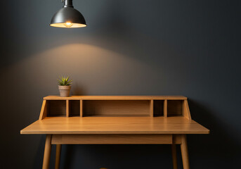A wooden desk with a small potted plant sits beneath a hanging lamp against a dark gray wall.