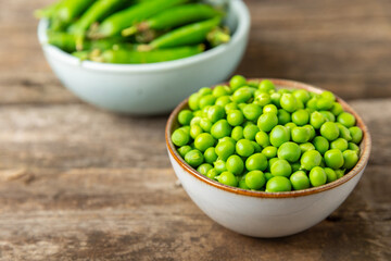 Fresh green pea pods with green peas on a wooden background. Sweet green peas. Green pea beans vegetables. Vegan. healthy vegetable. Copy space