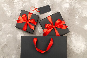 Black shopping bag and gift boxes on concrete background, top view. Black Friday concept
