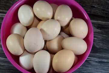 Bowl with organic fresh and raw hen chicken eggs, stack of eggs ready to be cooked in various...