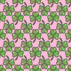 seamless pattern of green four-leaf clovers on a pink background, design in a cross-stitch style,