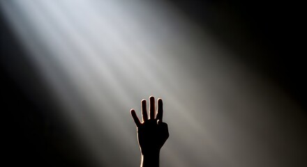 Silhouette of a hand with four fingers raised against dramatic light rays