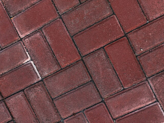 Detailed overhead view of a classic red brick sidewalk with interlocking clinker pavers arranged in a timeless herringbone pattern, ideal for architectural backgrounds