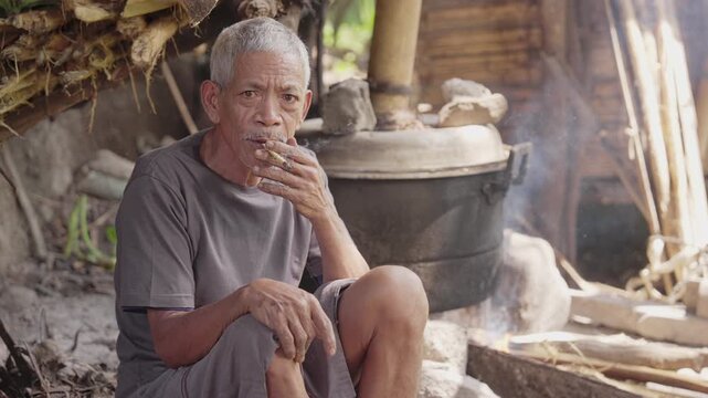 Indonesian farmer smoking traditional palm leaf cigarette in flores, indonesia, tobacco rolled in dried sugar palm leaf, paisok daun anau