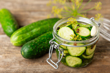 Freshly-salted homemade cucumbers in a jar on a wooden background. pickled cucumbers with dill,garlic and pepper.canned cucumbers.cucumbers and dill.Recipe of homemade preservations.fermented veggies.