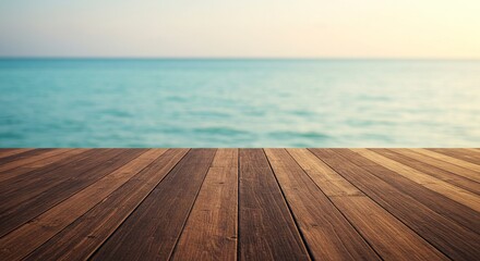 Brown wooden deck overlooks blurred turquoise water with a lighttoned sky in the background