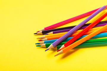 Colored pencils on a bright colored background. Equipment for coloring. Stationery for...