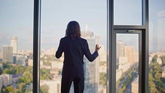 Lady boss quarrelling cellphone by panoramic window inside highrise building. 