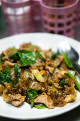 Pad See Ew, Thai stir fried rice noodles with pork and egg served on white dish