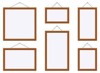 Isolated against a white background are six empty frames of varying sizes and orientations, each suspended from a thin wire, creating a clean and minimalist display.