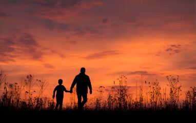 Fototapeta premium International migrants day concept: Silhouettes father and son holding hand in hand on meadow autumn sunset background