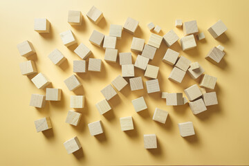 Wooden blocks scattered on yellow background. Abstract geometric pattern for business building, teamwork, and creative solution concepts.