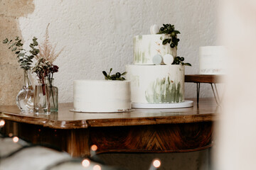 Elegant wedding cakes with greenery decoration on rustic wooden table