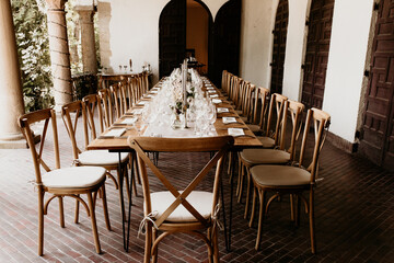 Elegant long wedding reception table setup with rustic chairs and floral decoration