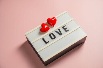 Word love with a red hearts over pink background