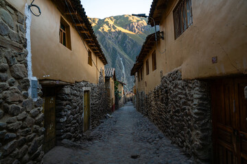 Eine schmale Gasse in Ollantaytambo, Peru, mit traditionellen Steinhäusern und Blick auf die Berge