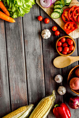 Autumn harvest. Vegetables - potato,cucumber, corn, greenery - frame on dark wooden background top-down copy space