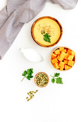 Pumpkin cream soup on white table top view. Autumn traditional meal
