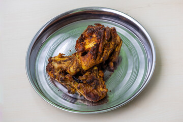 Tempting whole fried country chicken, seasoned and marinated with spicy BBQ spices, served on a steel plate. A savory and delicious homemade dish with crispy skin.