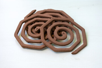 Close-up of several unlit mosquito coils in a spiral shape, isolated on a white background. Essential household insect repellent.