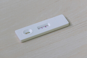 Luteinizing Hormone (LH) test kit showing a positive result with two lines on a wood background. This home ovulation test helps women identify their most fertile days.
