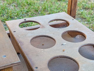 Wooden template board with multiple circular cutouts creating pattern holes for construction or...