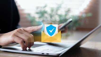 Hand using a laptop with a digital email security icon, showing online communication protection, safe data transfer, cyber privacy, secure business information, and digital verification concept.