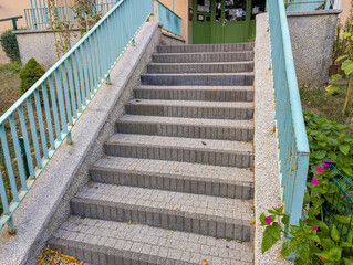 Concrete staircase with green metal railing leading upward through urban park or public space...