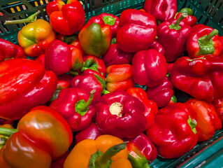 Vibrant red bell peppers and mixed colorful peppers arranged together creating striking vegetable display at market stand. high quality photograph