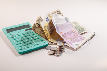 calculator with euro bills and a stack of coins on white background