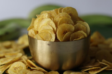Crispy plantain chips in golden bowl, made from green plantains. Kerala snack for comfort and taste