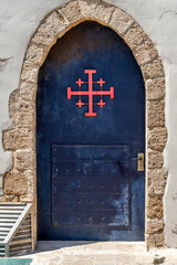 The blue door with the red Jerusalem Cross or Crusader Cross of Saint John's Baptist Church in the old city of Acre, Akko Israel.
