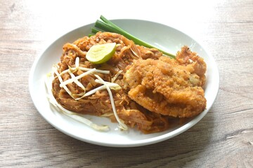 Pad Thai stir fried rice noodles with dry shrimp and egg topping crispy fried chicken on plate 
