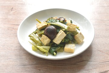 fried slice morning glory with tofu topping black mushroom in soy sauce on plate