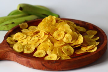 Plantain chips on wooden plate with raw plantains, South Indian snack evoking comfort and tradition