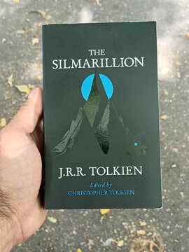 Hand Holding "The Silmarillion" by J.R.R. Tolkien Book Cover