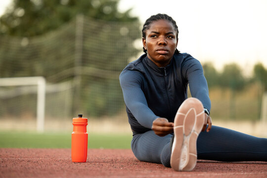 Motivated serious female athlete warming up and preparing for running training. Professional marathon runner.
