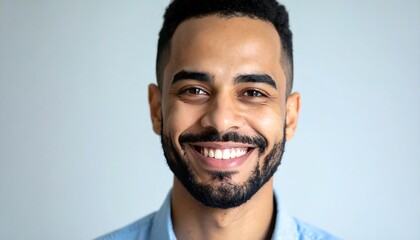 Fototapeta premium A cheerful man with a wide smile and a light blue shirt against a neutral background presents a positive and approachable demeanor.