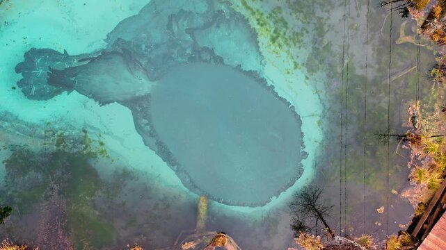 Beautiful Blue Geyser lake with thermal springs that periodically throw blue clay and silt from the ground. Aerial top down drone view. Geyser Lake is a natural attraction near Aktash, Altai mountains