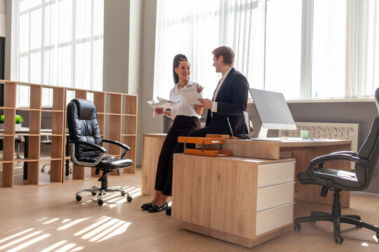office workers in business suit discussing documents in office at meeting, african american woman and caucasian man working and talking about report, general view