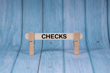 Checks symbol. Wooden stick clamped by Clothespins, vivid blue wooden backdrop. Business and Checks concept with copy space