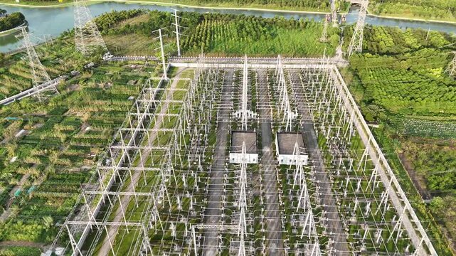 Drone video of an electric power substation and transmission towers surrounded by green farmland and waterways, symbolizing sustainable energy, infrastructure, and climate-friendly technology.