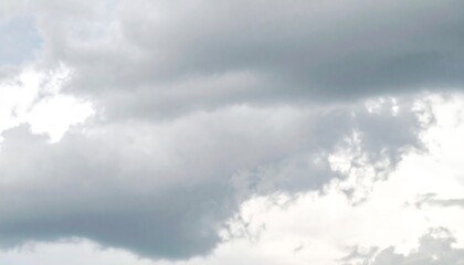 A serene, light gray sky is filled with various fluffy, white clouds, creating a tranquil and peaceful atmosphere.