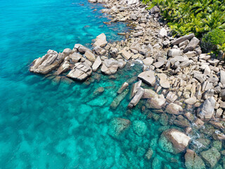 Seychelles aerial view, Praslin Island. Granite rock formations along a tropical shoreline with transparent turquoise waters and lush coastal vegetation. Exotic landscape.