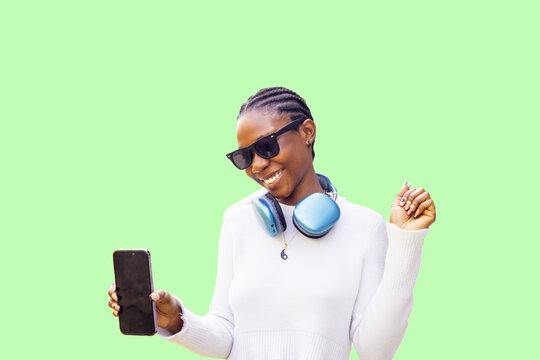 Smiling Woman with Headphones and Sunglasses Holding Smartphone