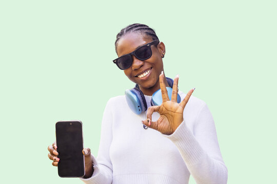 Young woman with sunglasses holding phone, showing 'OK' sign
