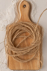 wooden cutting board with a beige jute rope in a spiral shape on top
