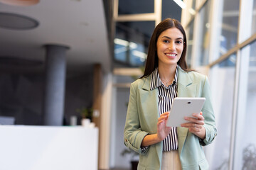 Professional businesswoman working on digital tablet, navigating corporate workspace with...