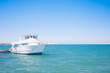 A white boat is anchored in a clear turquoise sea